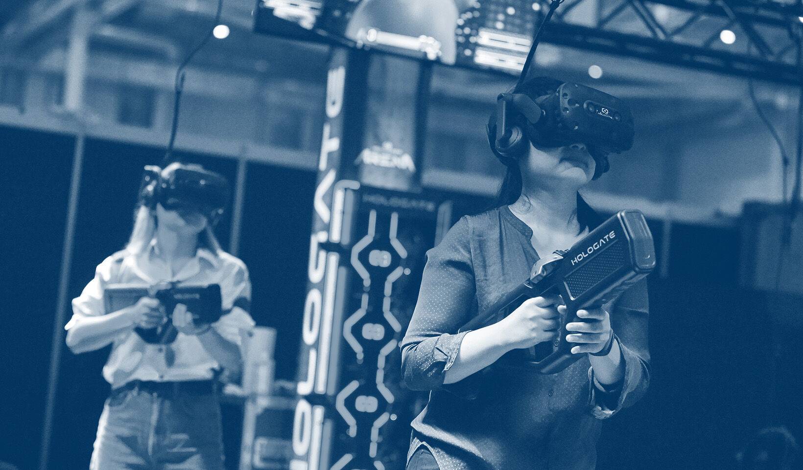 Zwei weibliche Personen mit VR-Brillen und  Spielzeuggewehren von Hologate