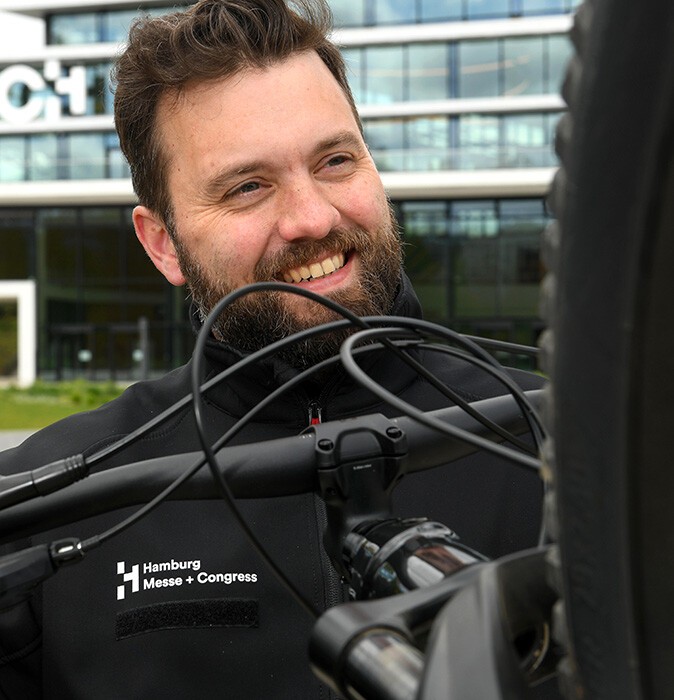 Tim Normann im Portrait mit dem Fahrrad im Vordergrund
