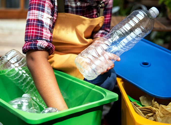 Plastikflaschen werden in einen Recyclingsammelbehälter gelegt