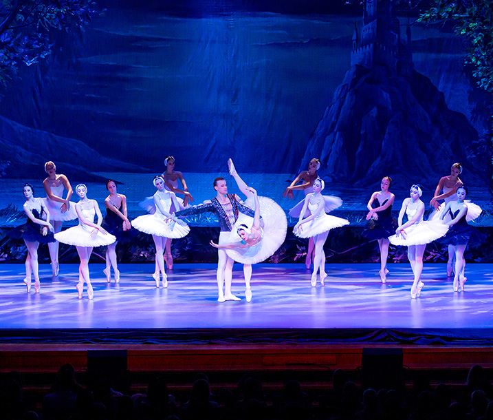 Szene der Ballettaufführung Schwanensee mit 13 Tänzerinnen in schwarzen und weißen Tutus sowie einem männlichen Tänzer